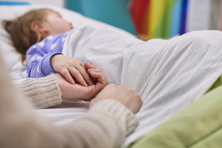 parent holding daughter's hand in the hospital bed